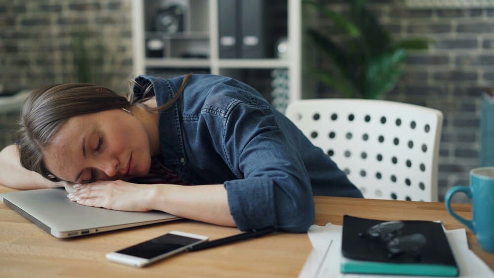 Femme fatiguée qui dort sur ses mains ménopause 